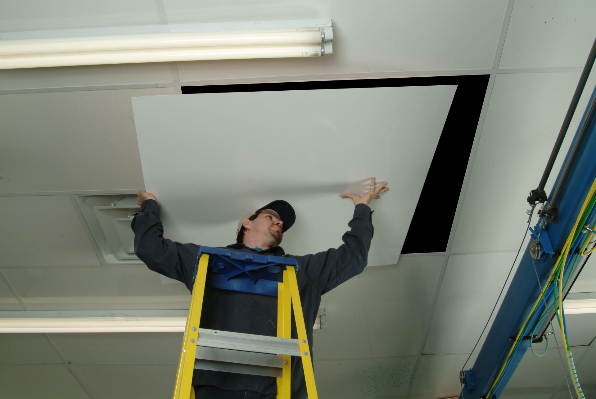 Pro-Glas installer fitting a fiberglass ceiling panel from a ladder