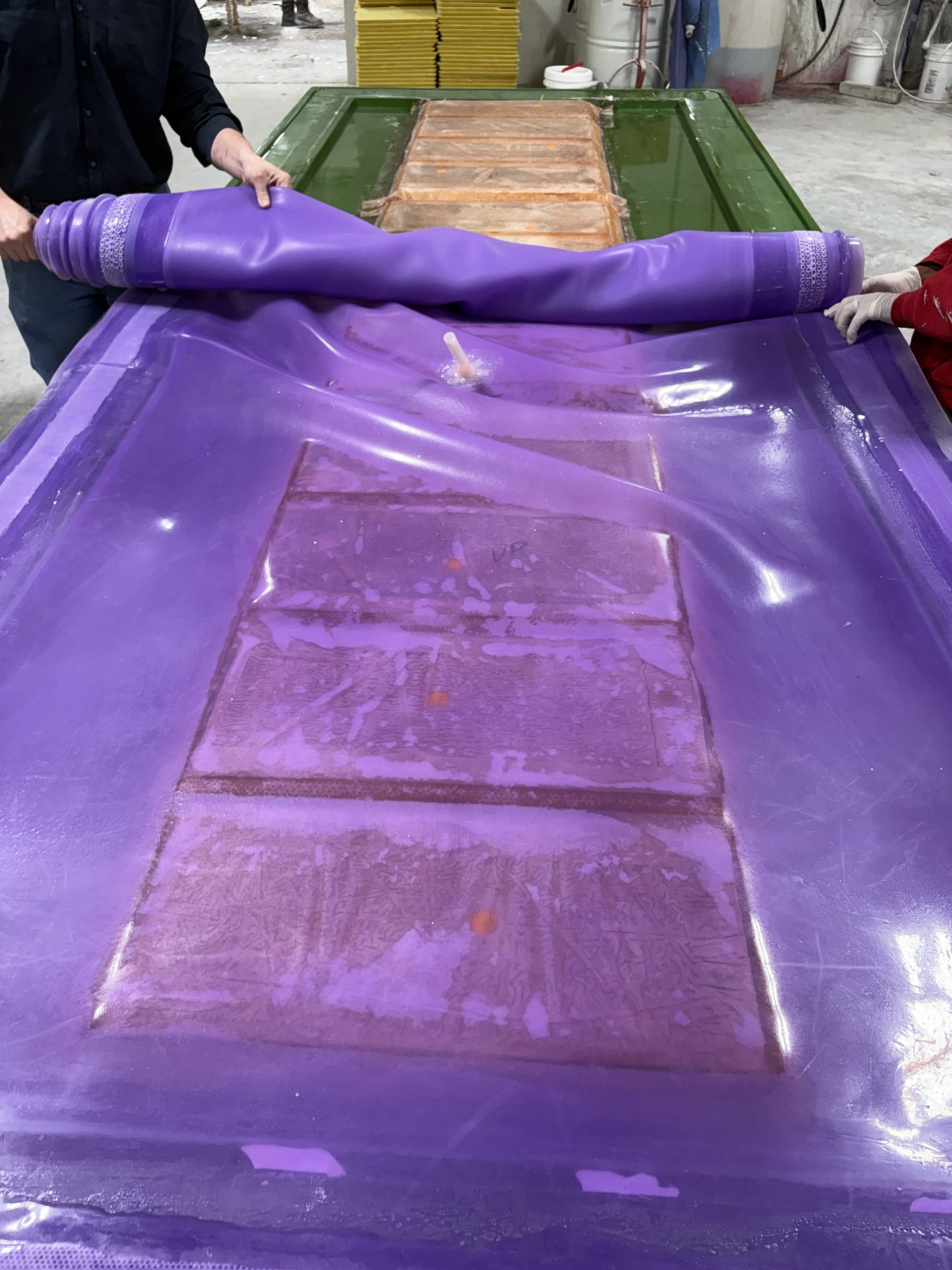 Crew rolling a reusable silicone membrane over molded panels