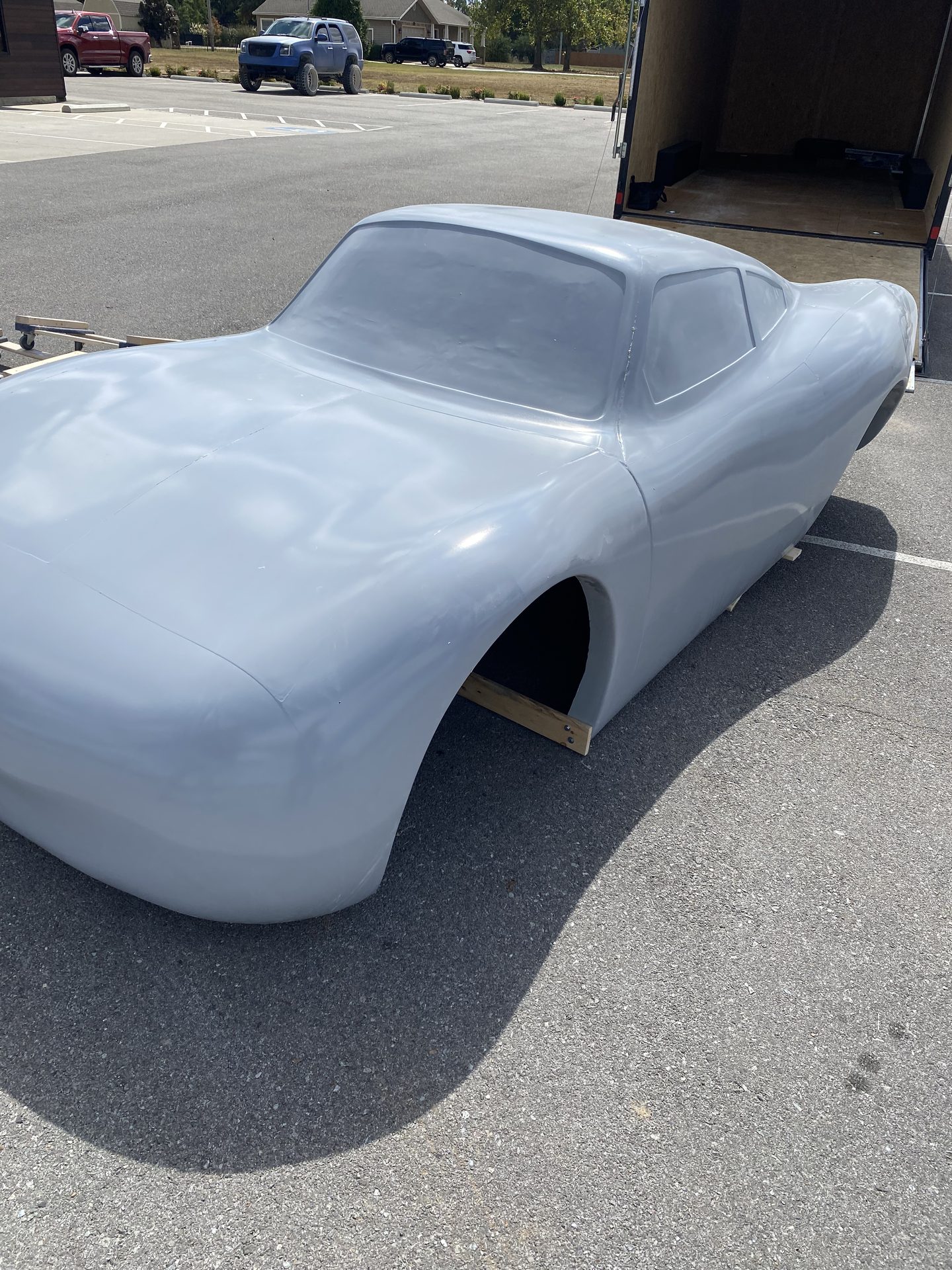 Full-size fiberglass race car body in gray primer outside the Pro-Glas shop