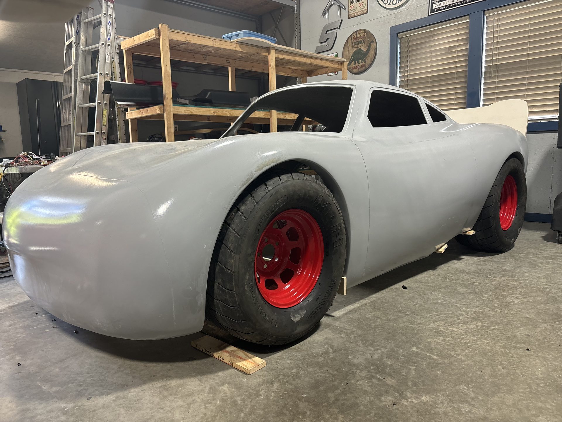 Fiberglass stock car body rolling on red steel wheels